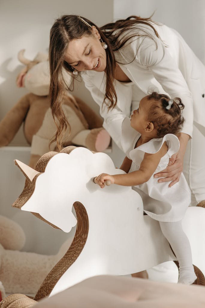 Happy mother and daughter enjoying playtime on a rocking horse indoors.